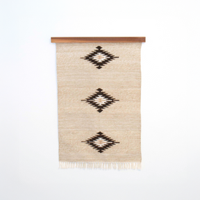 Chitki (Crisp) Wool Rug / Wall Hanging ($240) features a beige base with three black diamond patterns and comes with a wood hanger, crafted in an eco-friendly mill for a natural, artisan touch.
