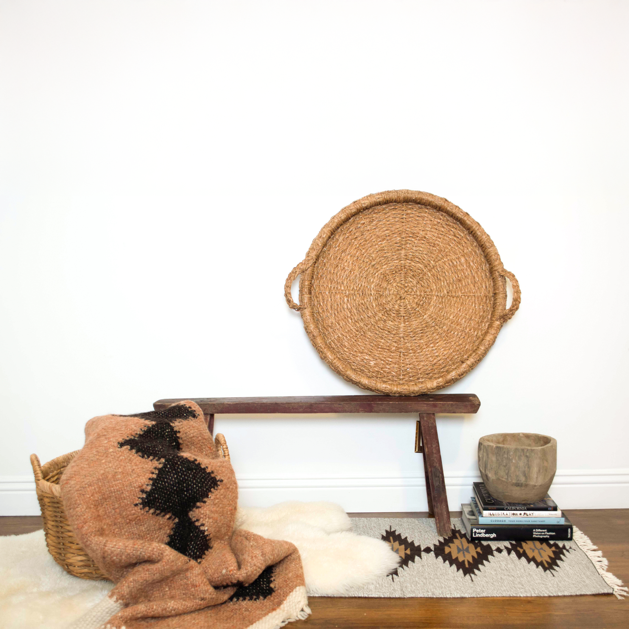 A Druh (Friend) Wool Statement Throw / Baby Blanket rests in a basket on a bench.