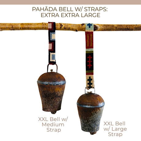 Two vintage handmade Pahāḍa bells from the Himalayan mountains of Nepal and Tibet hang from a branch, each with a colorful patterned strap. Perfect as Christmas ornaments, wreath decor, or for sound baths; each bell measures 11".