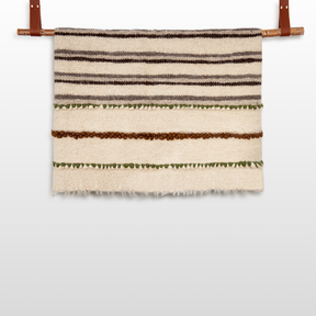 The Faino (Fine) Wool Statement Throw / Baby Blanket adds cozy, handcrafted charm to your space with its brown, green, and cream stripes—perfect draped on a rod or used as a warm accent.