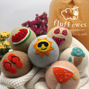 Six Fluff Ewes "Fun in the Sun" Premium Wool Dryer Balls (6 pack), eco-friendly natural fabric softeners with summer designs, pictured in front of a Fluff Ewes bag.