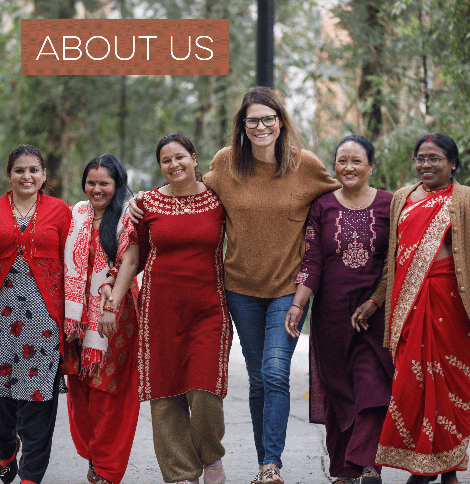 Six women, arm in arm, smiling and walking outdoors with 