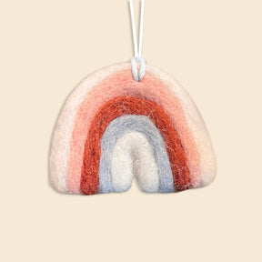 Rainbow is a hand-felted ornament with pink, red, and blue arches, crafted from New Zealand wool. Hanging by a white string against a beige background, it makes a charming addition to any artisan Christmas ornament collection.