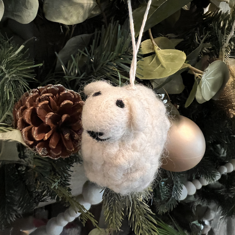 The Large Mama Sheep, a white hand-felted ornament made from New Zealand wool, hangs on the Christmas tree near a pine cone and gold bauble, bringing charm to your collection of artisan holiday decorations.