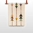 The Lis (Forest) Wool Statement Throw / Baby Blanket features a beige woven design with geometric arrow patterns in brown, green, yellow, and orange, reminiscent of handwoven art, and is displayed hanging from a rod.