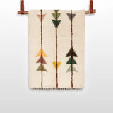 The Lis (Forest) Wool Statement Throw / Baby Blanket features a beige woven design with geometric arrow patterns in brown, green, yellow, and orange, reminiscent of handwoven art, and is displayed hanging from a rod.