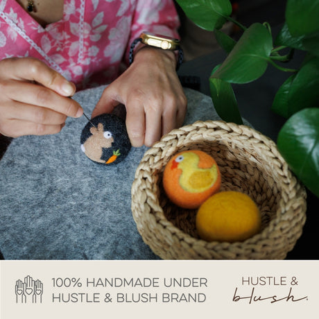 A person needle-felting animal designs beside a basket with felted eggs, using Love Ewe Handmade Felt Pet Toys for Cats, Kittens, Dogs, and Small Pets, 3-Pack, eco-friendly, natural dye, By Sea or Sky.