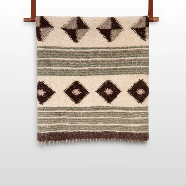 The "Handmade in Ukraine, Organic Natural 100% Sheep Wool Woven Statement Blanket Bed Covering Bedspread Duvet" features brown and green stripes with diamond patterns and hangs elegantly on a wooden rod.