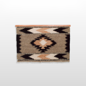 The Myr (Peace) Wool Wall Hanging is handcrafted with geometric patterns in beige, brown, and black, woven from undyed yarn and displayed on a wooden rod.