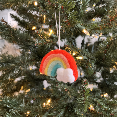 The Pair of Hand-Stitched Felted Rainbow Ornaments, crafted from New Zealand wool, hang on the Christmas tree among twinkling string lights.
