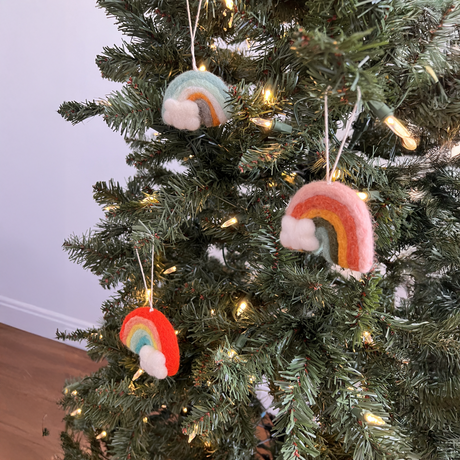 A Christmas tree adorned with a Pair of Hand-Stitched Felted Rainbow Ornaments, cloud felt accents, and string lights.