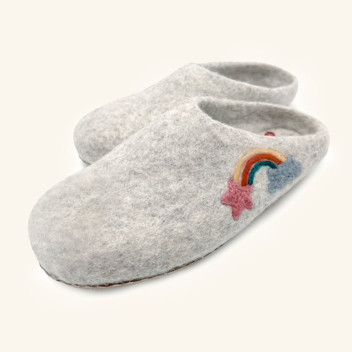 Love Ewe Hand-Felted Organic Wool Slippers for Women (Rainbow-Light) have hand-sewn soles and feature a rainbow, blue cloud, and pink star embroidered on the gray felt top.