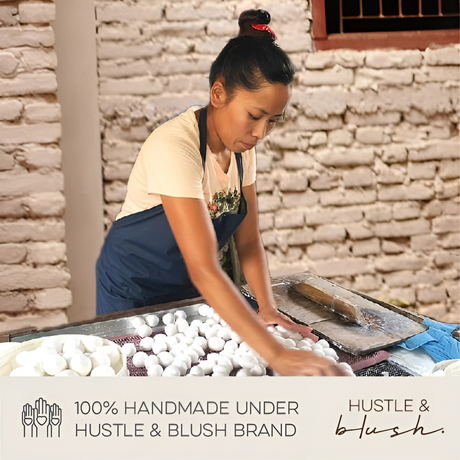 Woman shaping white handmade items on a table, with text promoting Hustle & Blush's fair trade Nepal wool School Boy Mouse ornament and handmade Christmas ornaments.