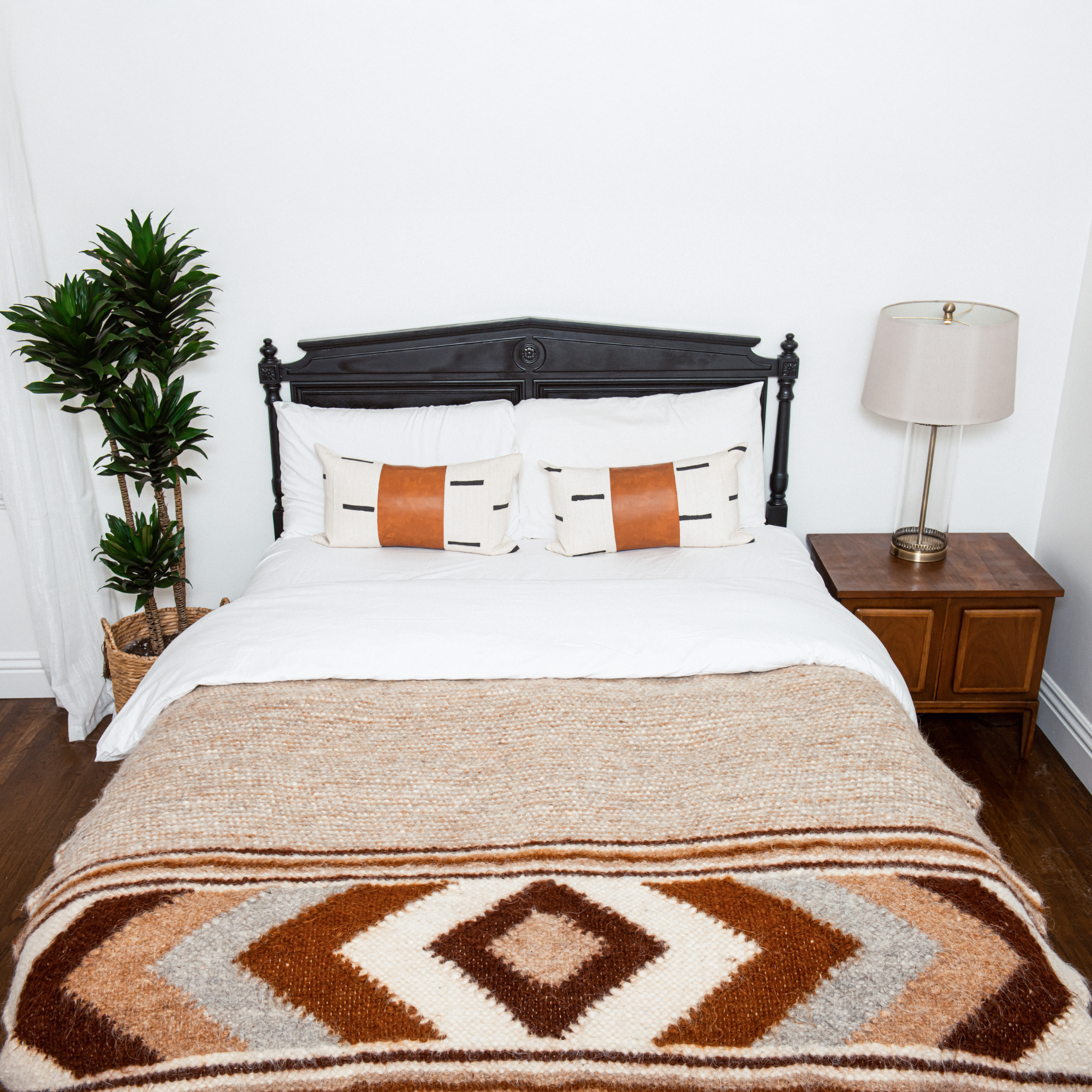 A bed with pillows, a lamp, and the Tkach (Weaver) Wool Statement Bed Blanket adds cozy charm to the room.
