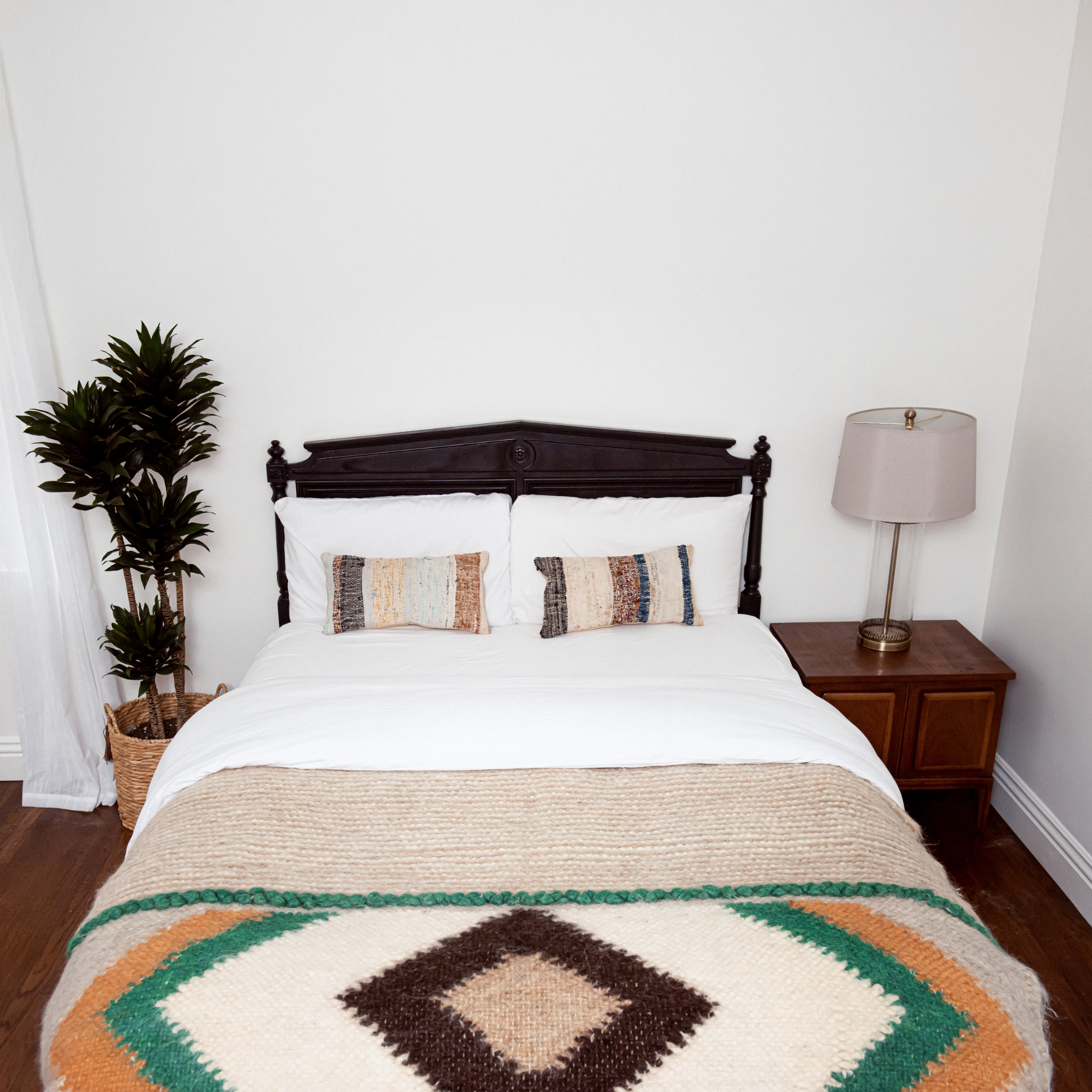 A bed features the Tkach (Weaver) Wool Statement Bed Blanket, complemented by pillows and a lamp for added style.