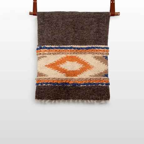 The Tkach (Weaver) Wool Statement Bed Blanket features a geometric diamond pattern in orange, cream, brown, and blue tones, crafted by Ukrainian artisans.