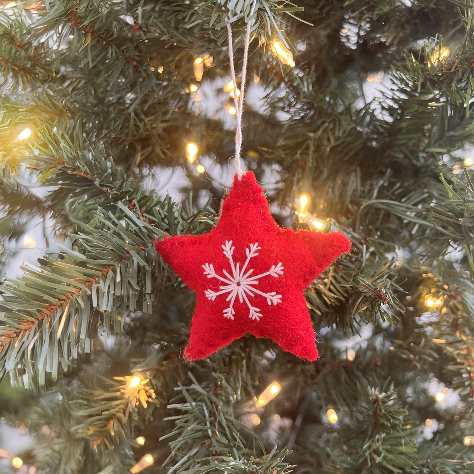 A Trio of Hand-Stitched Felt Stars and Heart Ornaments, crafted from sustainable wool, adds festive charm to the Christmas tree.