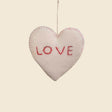 The Trio of Hand-Stitched Felt Stars and Heart Ornaments features a white wool heart with "LOVE" in red thread, hand-felted for a sustainable, artisan look. Hang these festive decorations to add charm to your holiday décor.