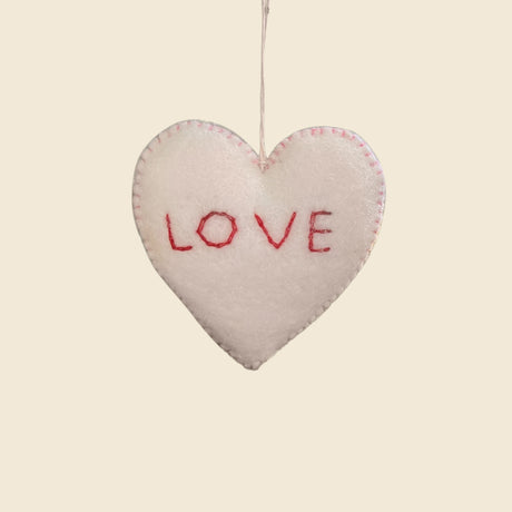 The Trio of Hand-Stitched Felt Stars and Heart Ornaments features a white wool heart with "LOVE" in red thread, hand-felted for a sustainable, artisan look. Hang these festive decorations to add charm to your holiday décor.