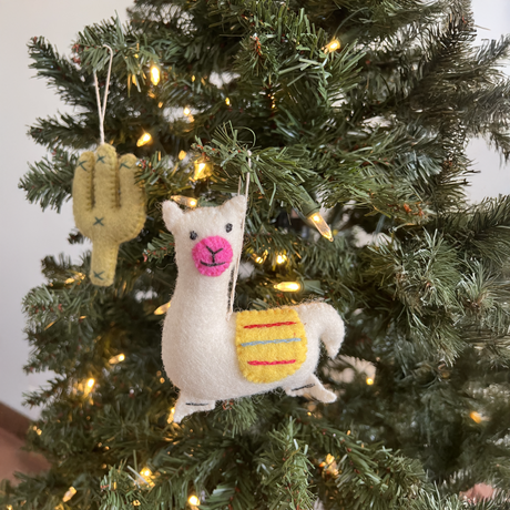 Trio of Hand-Stitched Felted Llama Ornaments hang on a Christmas tree with glowing string lights, bringing artisan charm to your holiday decor.
