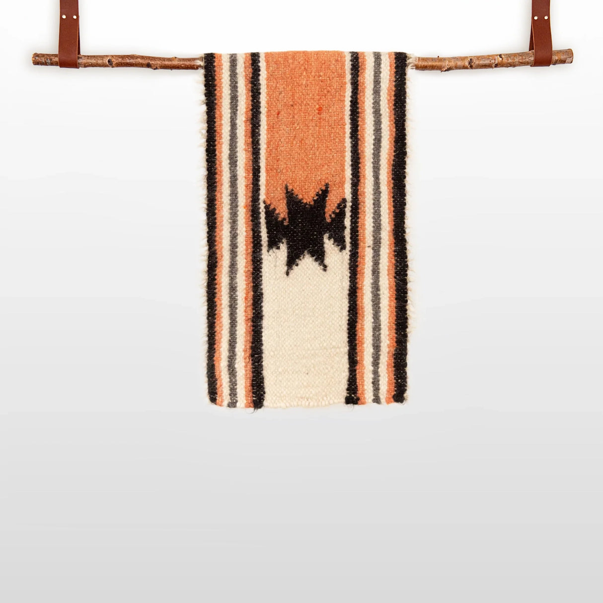 The Opora (Pillar) Wool Bed/Couch Runner, handcrafted from Carpathian sheep’s wool, features black star patterns and stripes. Hung with leather straps on a branch, it doubles as a striking bed or couch accent.