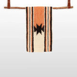 The Opora (Pillar) Wool Bed/Couch Runner, handcrafted from Carpathian sheep’s wool, features black star patterns and stripes. Hung with leather straps on a branch, it doubles as a striking bed or couch accent.