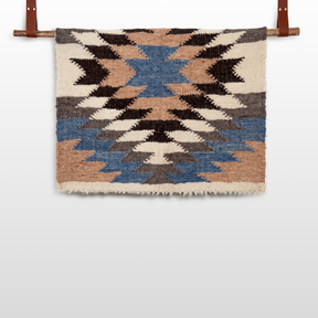 The Zirka (Star) Wool Statement Throw / Baby Blanket features a geometric zigzag pattern in blue, brown, black, and cream—an eye-catching artisan accent that adds charm to any space.
