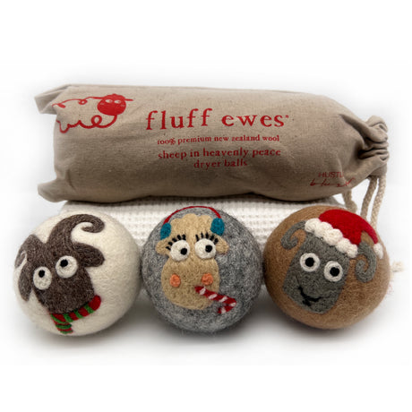 The Fluff Ewes Premium XL Dryer Balls "Sheep in Heavenly Peace" Holiday Limited Edition 3 pack features festive sheep-faced wool balls and a branded cloth bag—an eco-friendly, natural fabric softener for your laundry.