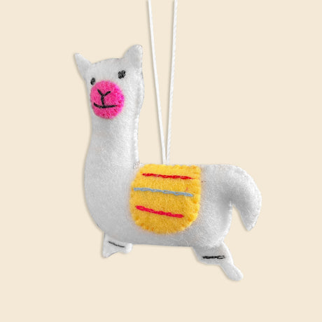 The Hand-Stitched Felted Llama Ornament is crafted from white wool, features a yellow saddle, pink cheeks, and a hanging string—ideal for fans of artisan Christmas ornaments.