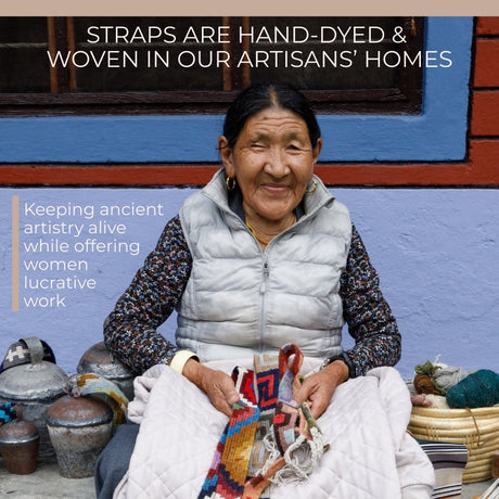 Smiling woman holding a Vintage Handmade Pahāḍa Yak, Goat & Sheep's Bell from the Himalayas, sitting by pottery and textiles against a bright painted wall.